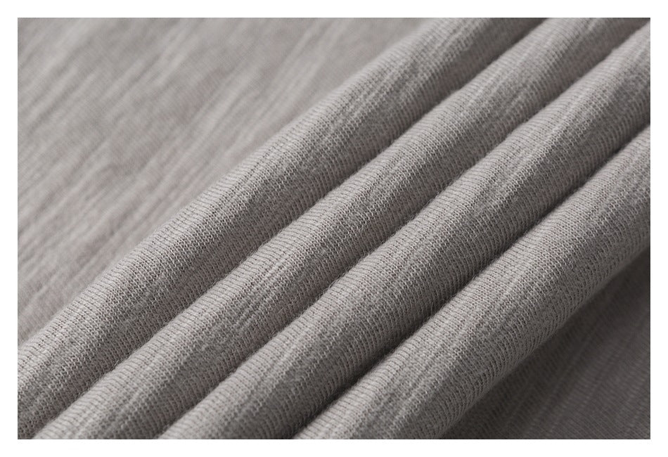 Close-up of light gray fabric draped into soft folds, showing its fine texture.