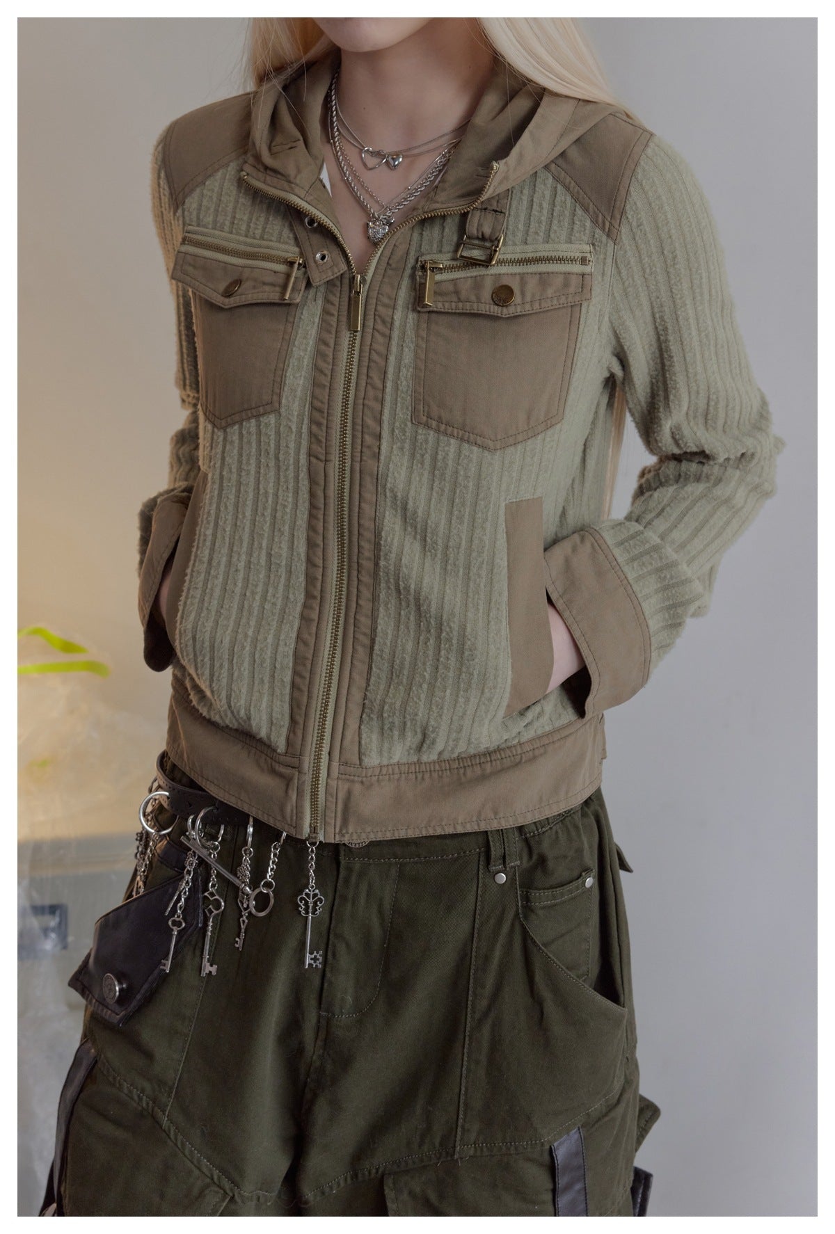 Model wearing a sage ribbed hooded jacket with taupe panels, zip pockets and a front zipper.