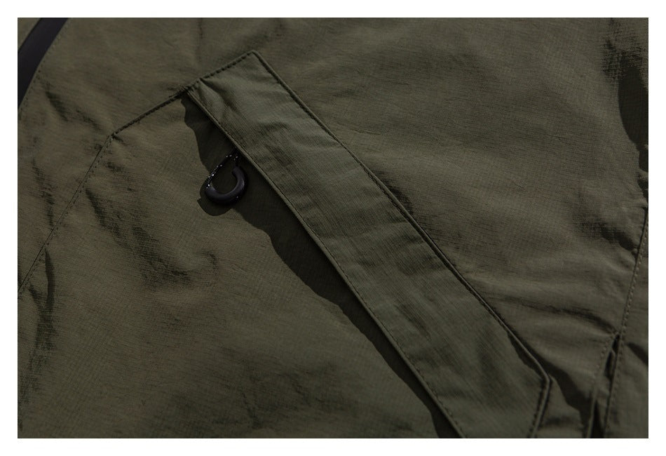 Close-up of an olive garment panel with a diagonal fabric tab and small black loop.