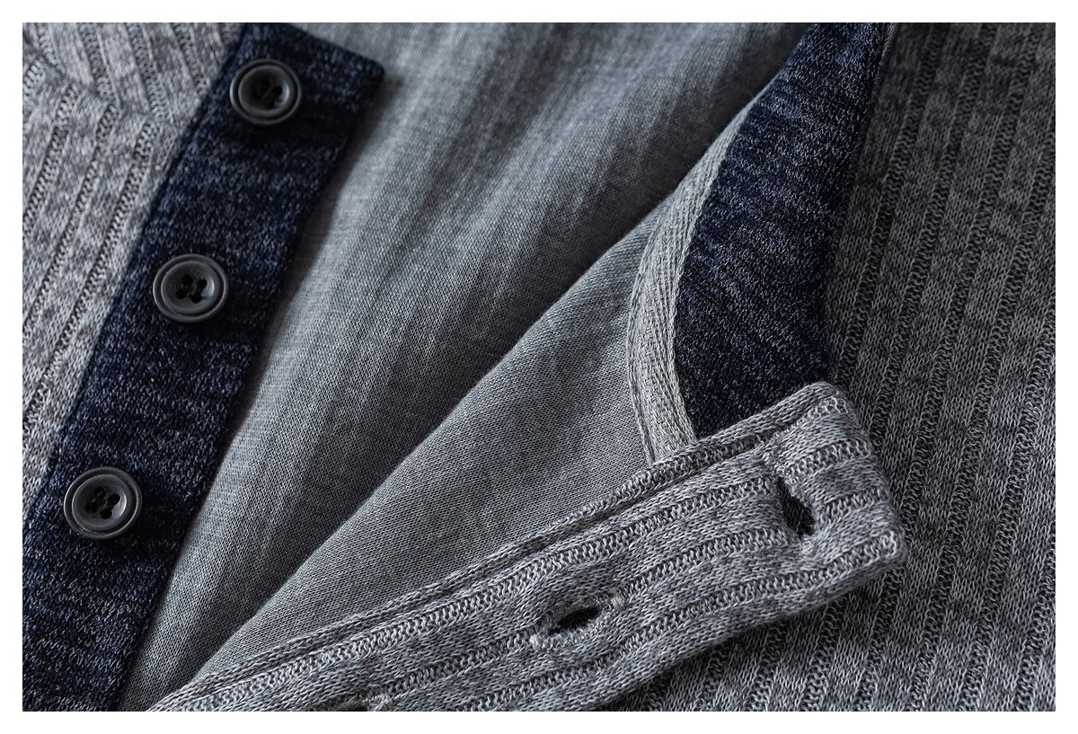 Close-up of a gray knit garment's dark button placket, buttons, inner facing and buttonholes.