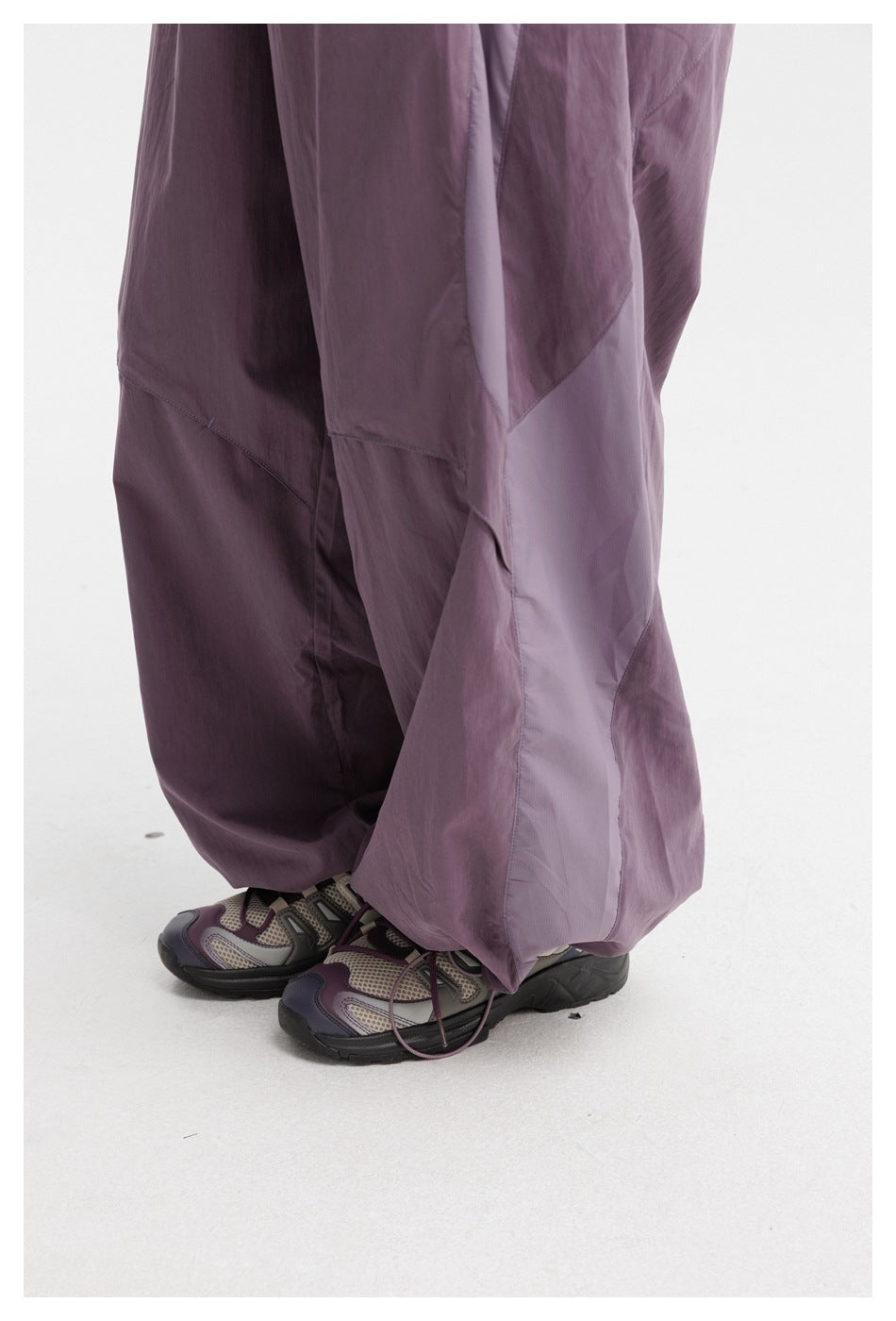 Close-up of the plum-purple pants' loose lower legs, contrasting panels, and gathered hems.