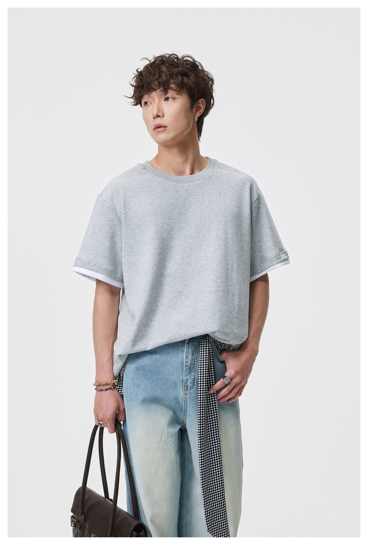 Closer front view of a model wearing an oversized light gray tee with white trim beneath the sleeves.