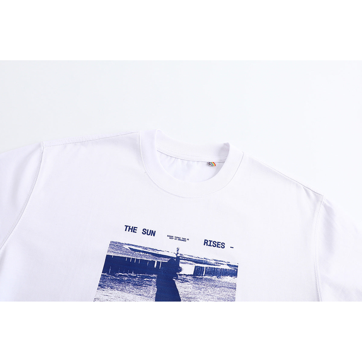 Cropped view of a white crew-neck T-shirt with a navy photographic graphic and text on the chest.