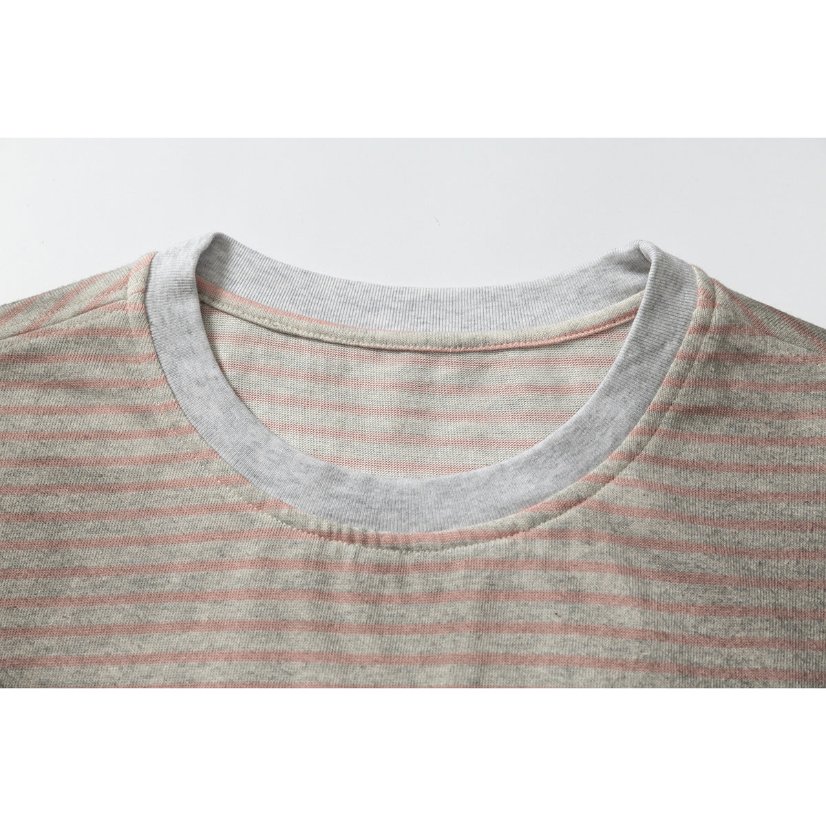 Close-up of a gray ribbed crew neck on a heather gray and dusty pink striped T-shirt.