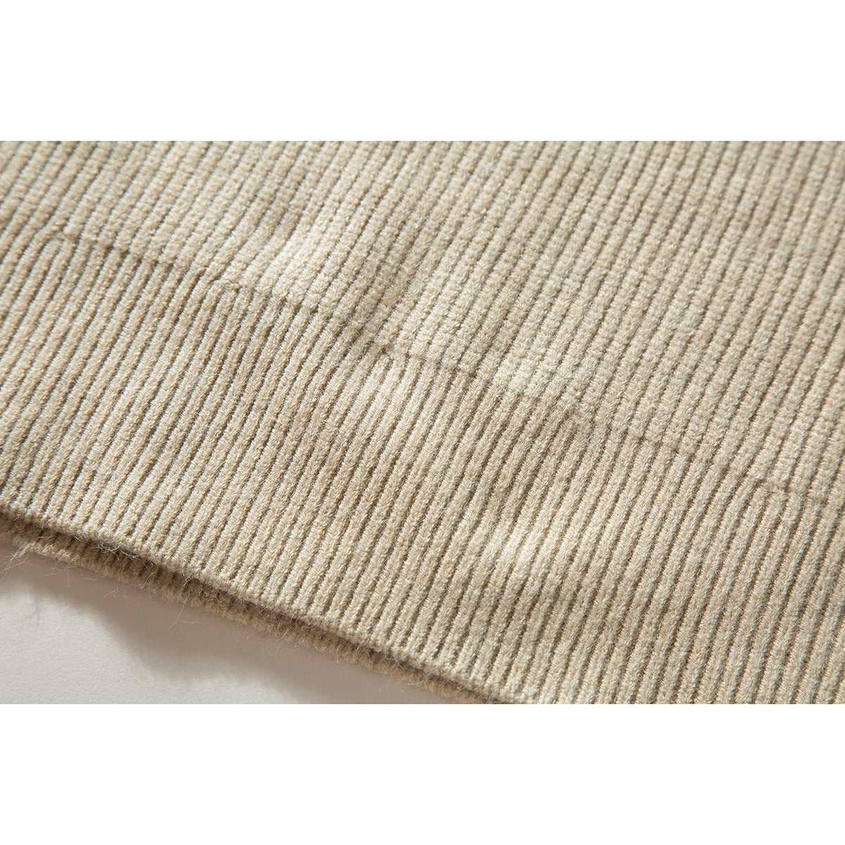 Close-up of cream rib-knit sweater fabric and finished edge.