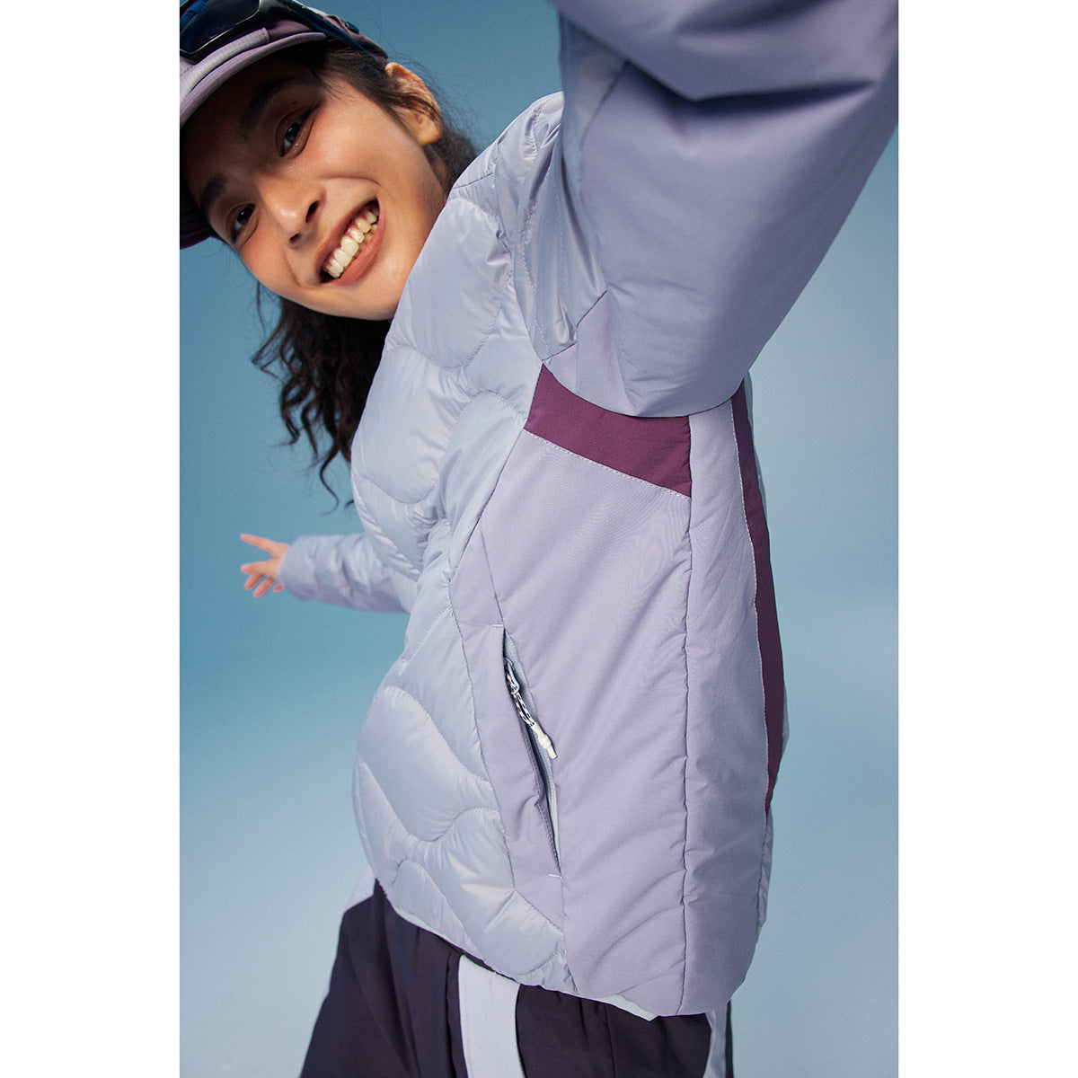 Close-up of a model wearing a pale lavender jacket with plum contrast panels and a front zipper.