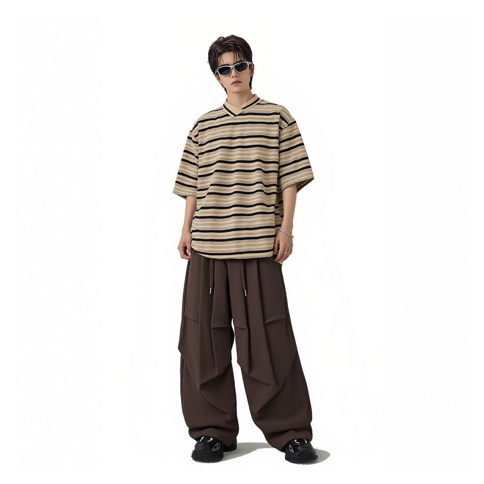 Front view of a model wearing a beige and black striped oversized collared T-shirt and dark wide-leg pants.