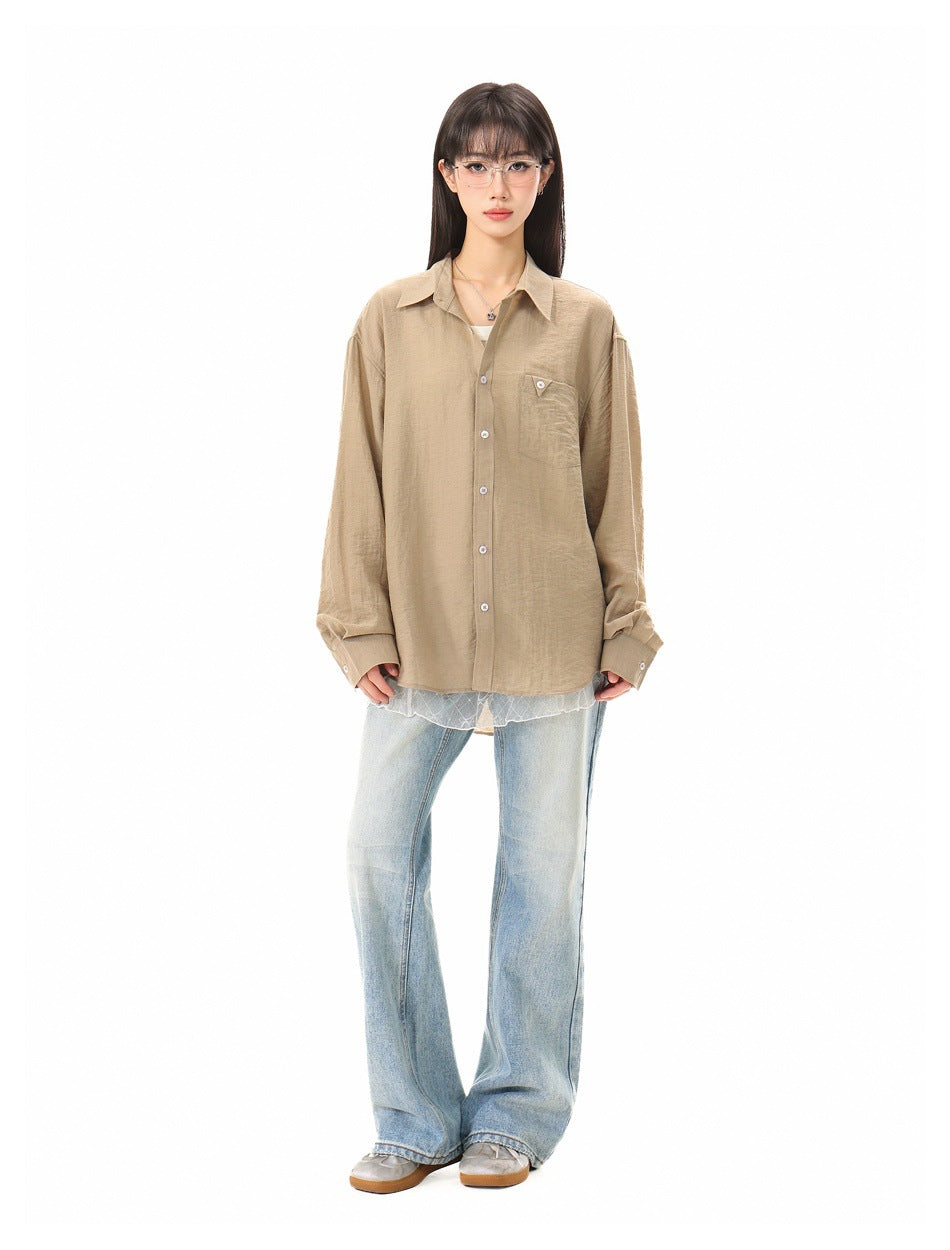 Full-length front view of a model in an oversized tan button-up shirt, light blue jeans, and sneakers.