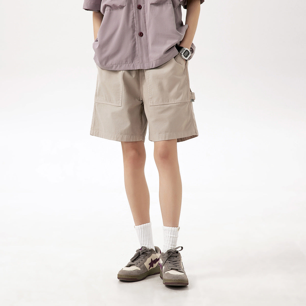 Model wearing beige cargo shorts with large front patch pockets; shown from the waist down.