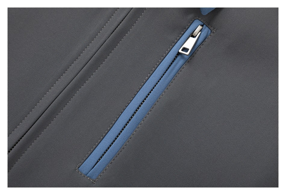 Close-up of a blue-trimmed diagonal zip pocket on charcoal jacket fabric.
