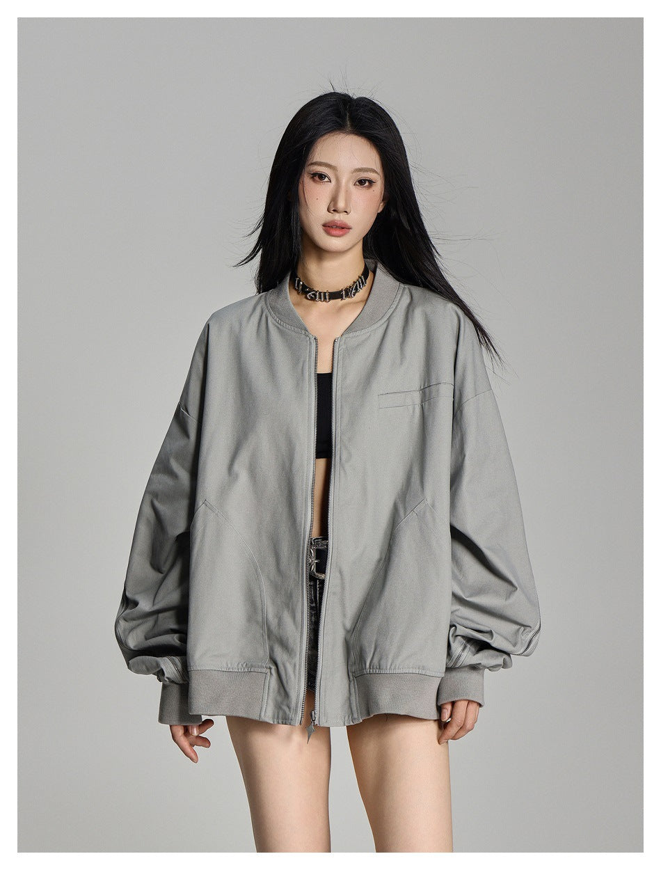 Front view of a model wearing a light gray oversized zip jacket with a small chest pocket, curved hand pockets and ribbed
