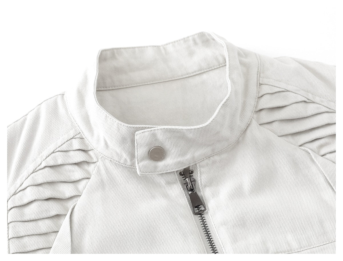Close-up of an off-white jacket's stand collar, snap tab, center zipper, and pleated shoulder panels.