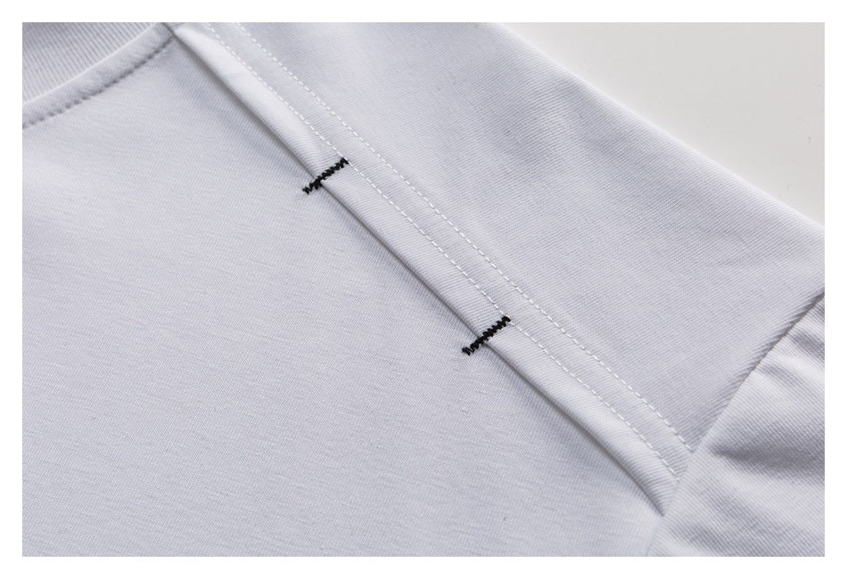 Close-up of a white T-shirt shoulder seam with two short black reinforcement stitches.