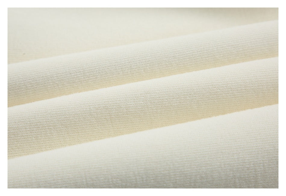 Close-up of ivory knit fabric showing a fine ribbed texture in parallel folds.