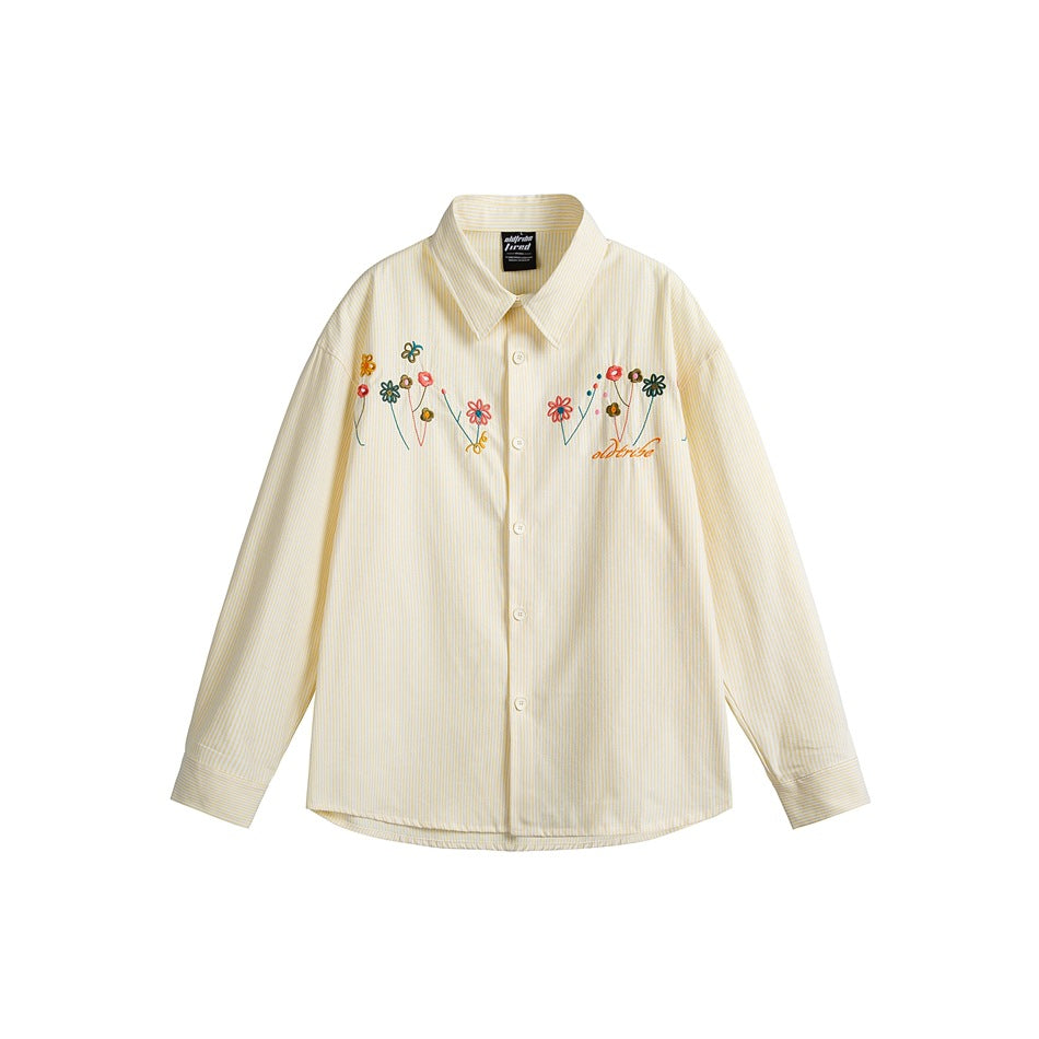 Front view of a cream pinstriped button-up shirt with a pointed collar and colorful floral embroidery across the chest.