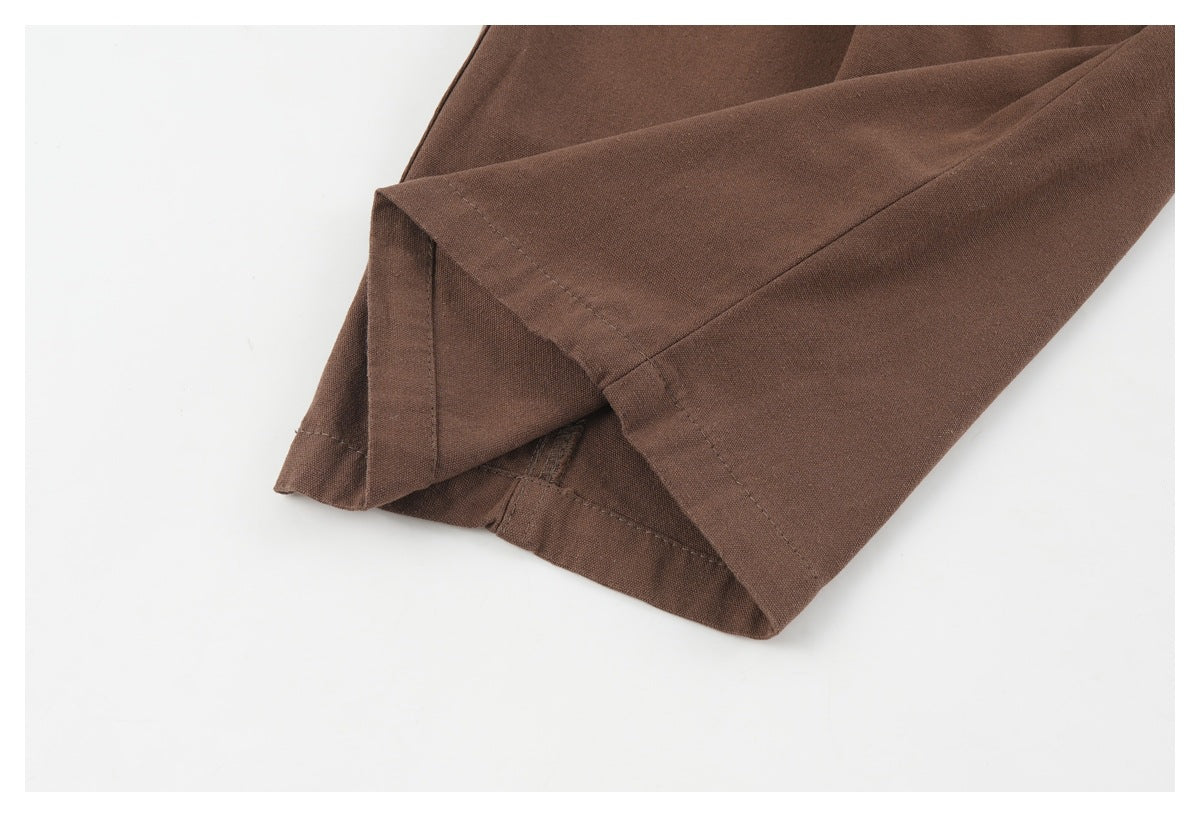 Close-up of the stitched hem on a brown trouser leg, folded to show the inside seam.