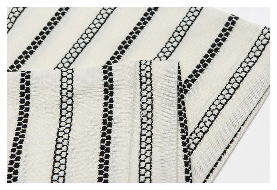 Close-up of ivory fabric with black patterned stripes and a folded edge.