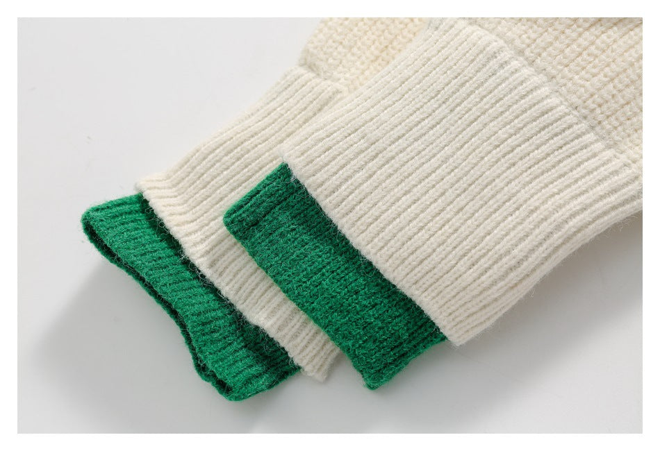 Close-up of folded ivory rib-knit fabric with emerald green sections at the edge.