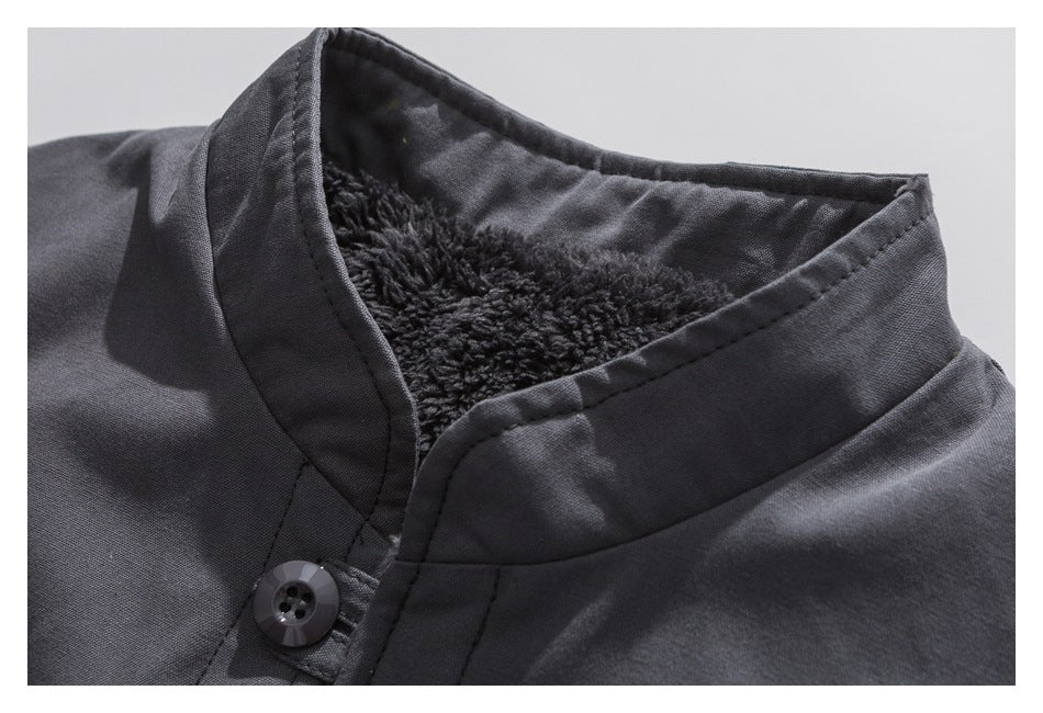 Close-up of a charcoal jacket collar showing dark plush lining, stitched edges, and a black button.