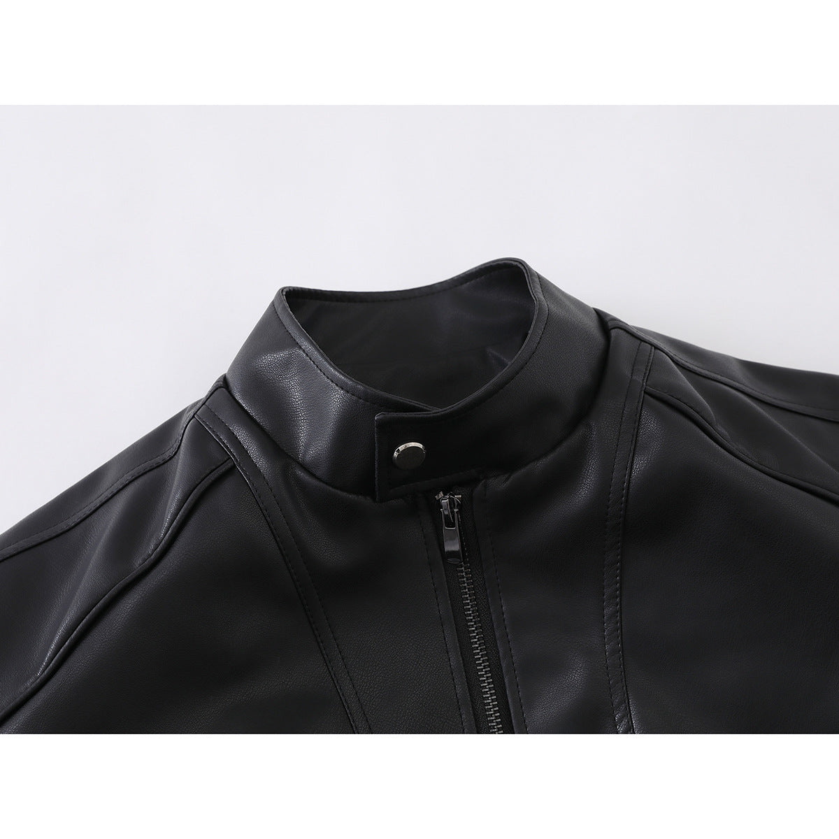 Close-up of a black jacket's stand collar, snap tab, front zipper, and stitched panels.