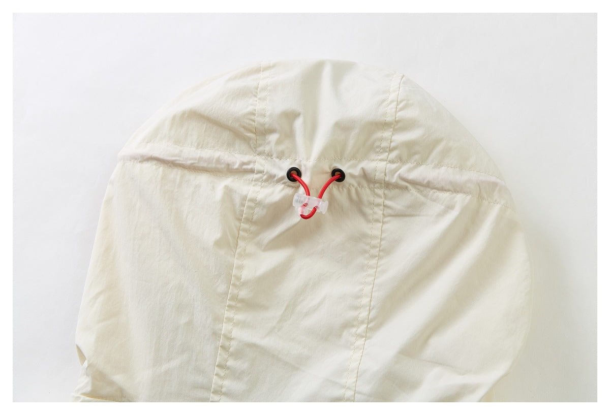 Close-up of a cream hood with red drawcords threaded through black eyelets and a clear cord lock.
