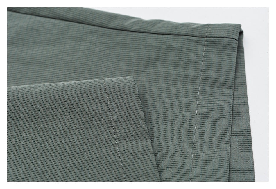 Folded gray-green striped fabric showing stitched hems and seams against a white background.