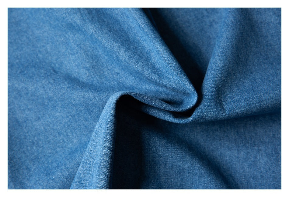Close-up of blue woven fabric draped into folds, showing its textured surface.