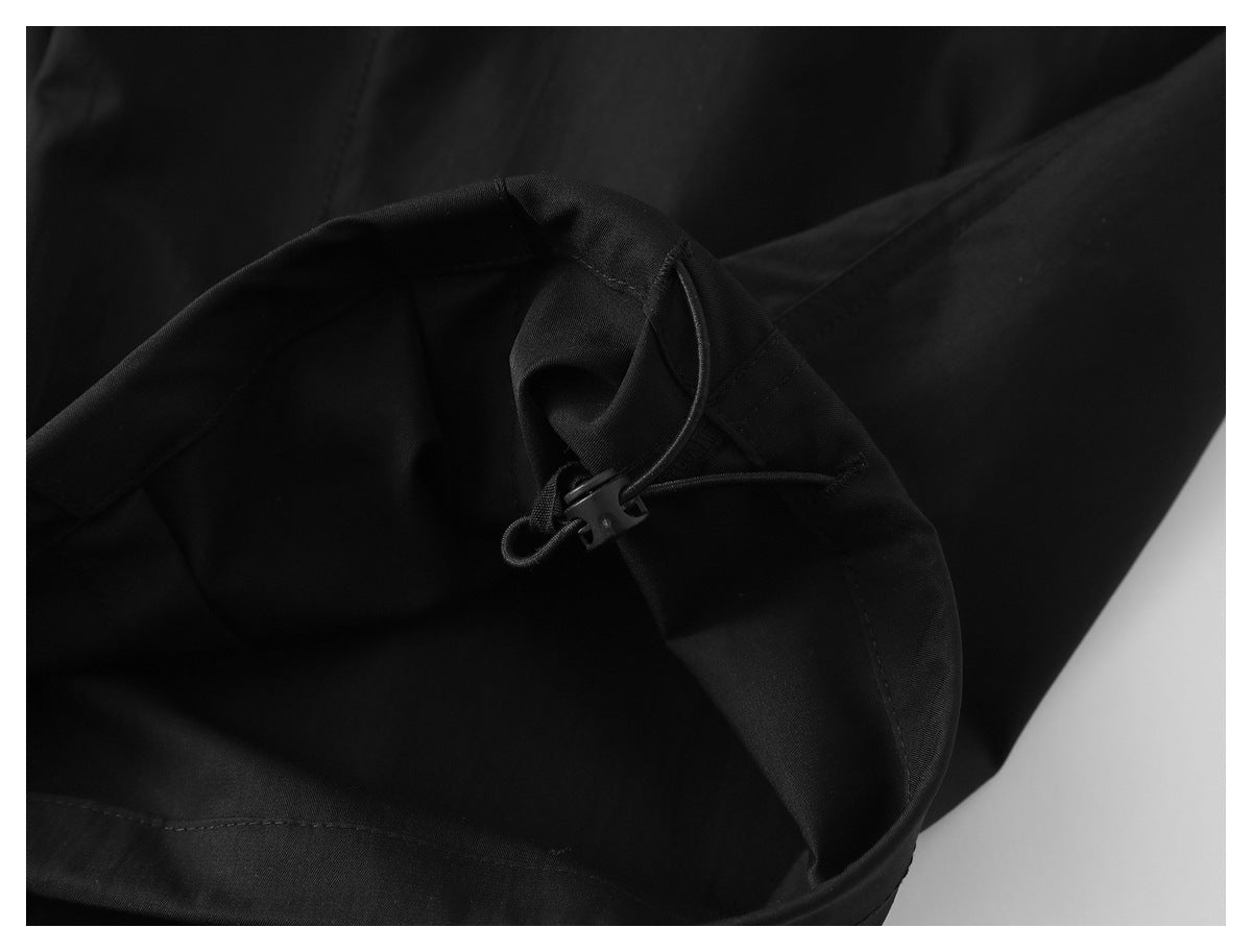 Close-up of black garment fabric with a cord and plastic toggle.