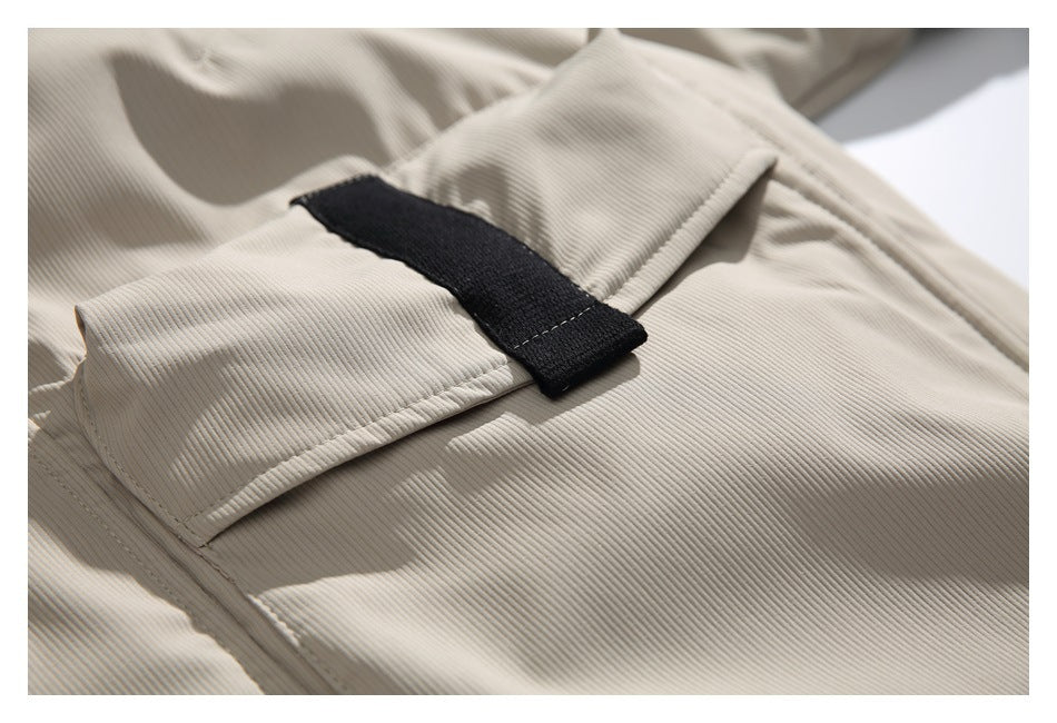 Close-up of a beige ribbed jacket with a flap pocket and a black fabric tab.