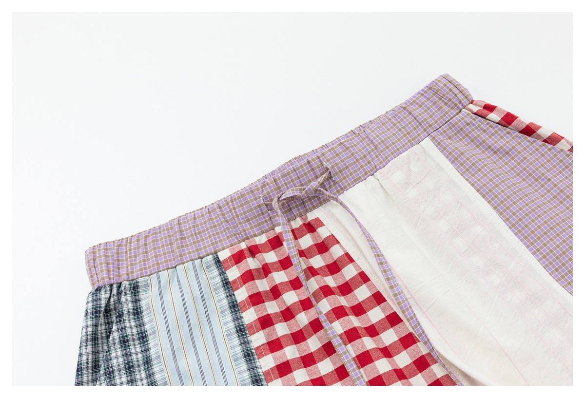 Angled close-up of the elastic lavender-check waistband, drawstring and red gingham, white and blue plaid panels.