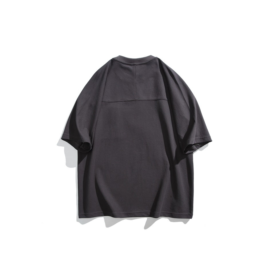 Back view of a charcoal oversized T-shirt with short sleeves and a horizontal yoke seam across the upper back.