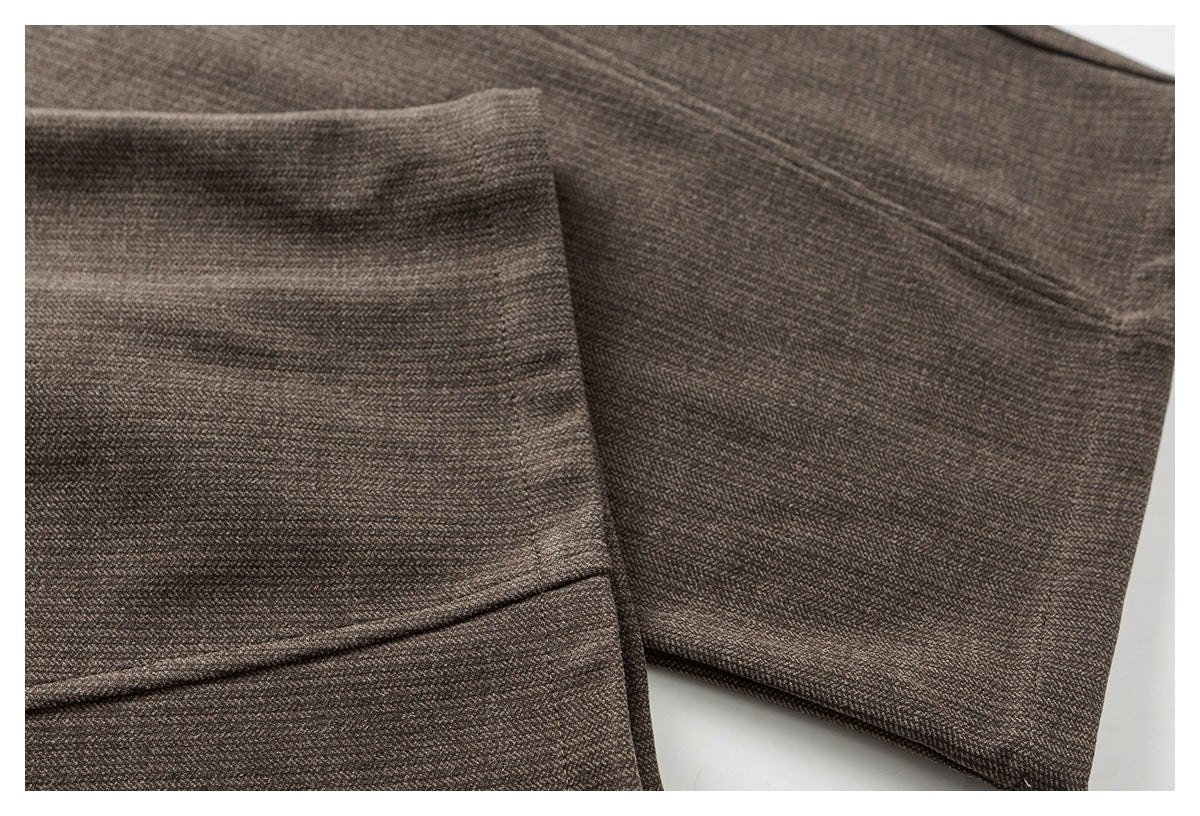 Close-up of a trouser leg showing the taupe fabric, seam, and folded hem.