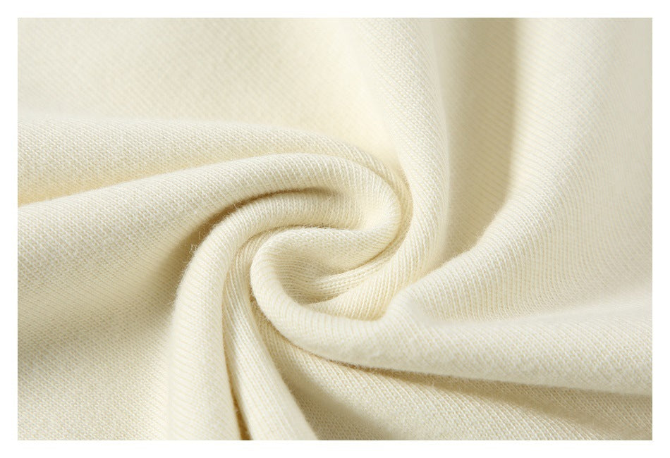 Close-up of soft-looking cream fabric gathered into a swirl to show its drape.