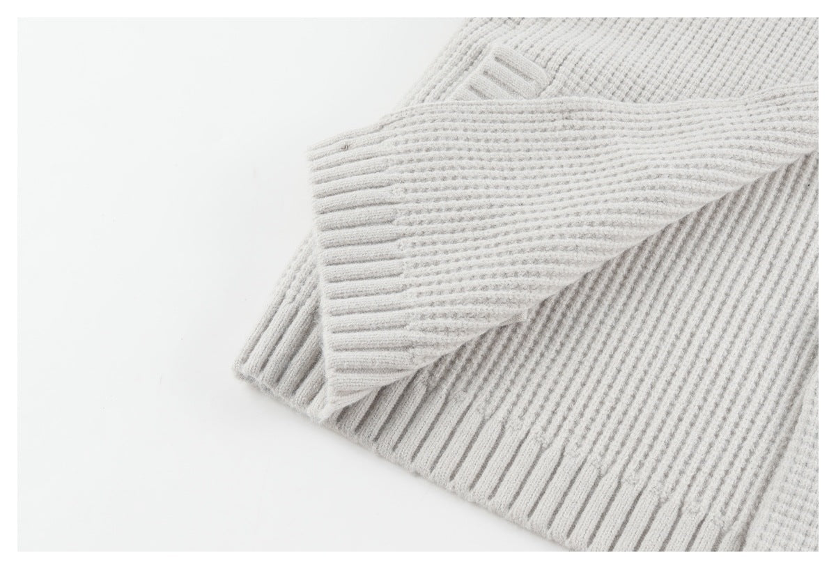 Close-up of a light gray rib-knit cardigan showing folded ribbed edges and cuff.