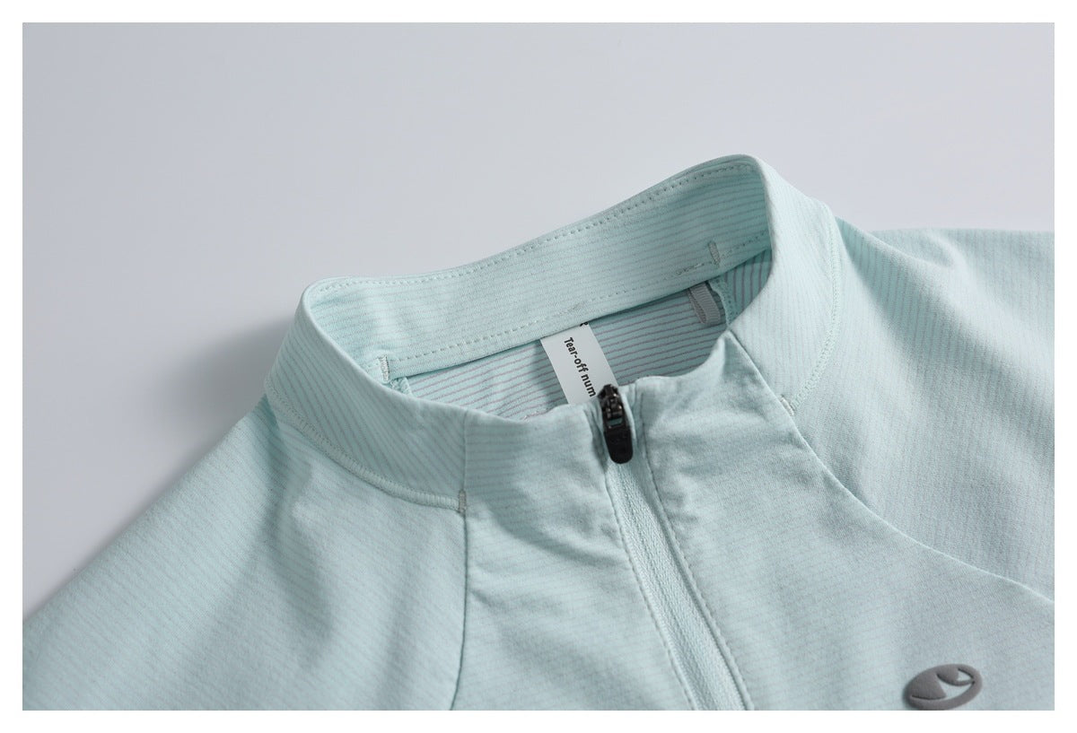 Close-up of a pale aqua zip-up top with a stand collar, fine stripe texture, and a small gray chest emblem.