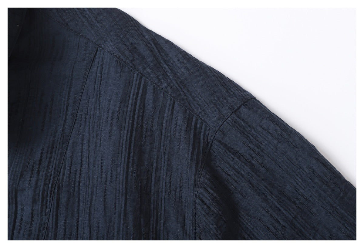 Close-up of a dark navy garment shoulder and sleeve seam with a raised, subtly striped texture.