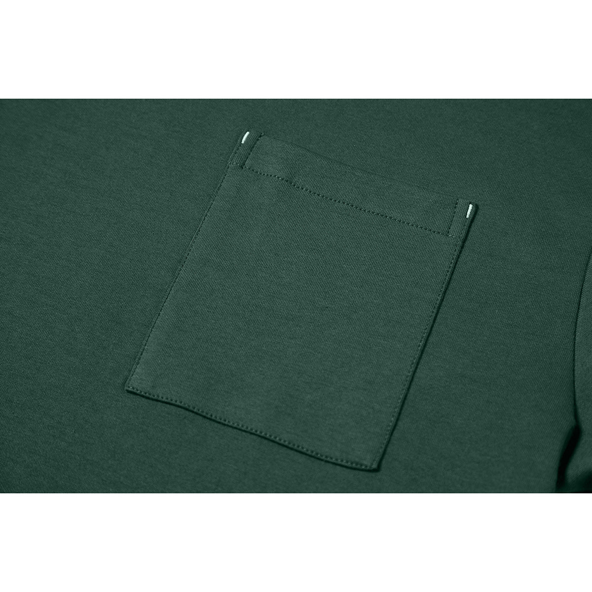 Close-up of a dark green T-shirt's square chest pocket with reinforced upper corners.