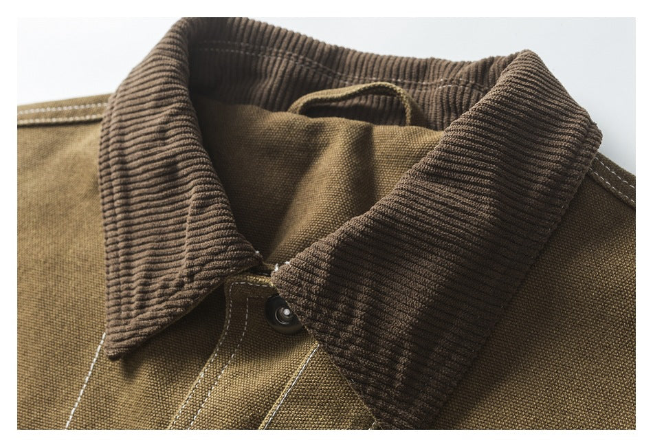 Close-up of the jacket's dark ribbed corduroy collar, upper canvas body, and button fastening.