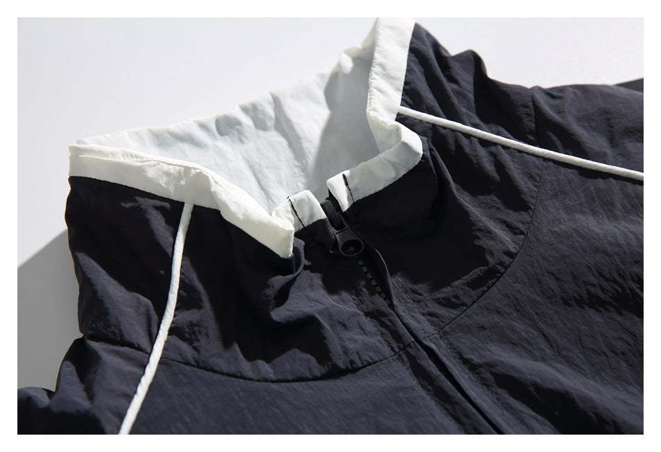 Close-up of the windbreaker’s white-lined stand collar and black front zipper with white piping.