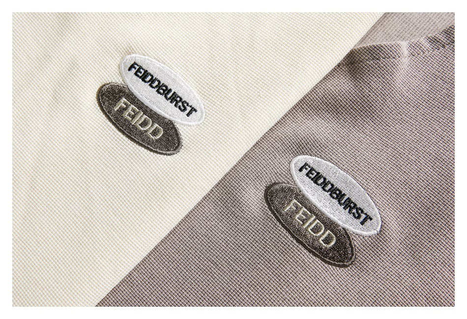 Close-up of embroidered oval patches on ivory and light gray tops.
