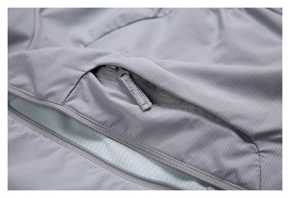 Close-up of an open zippered pocket on gray vest fabric, showing its dark mesh lining.
