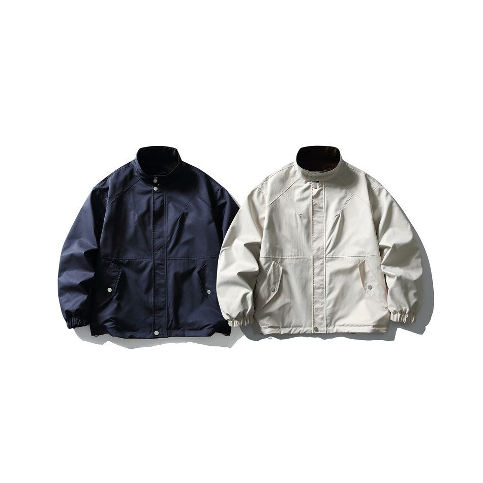 Two front-facing stand-collar jackets shown together in navy and ivory, with snap closures and gathered cuffs.