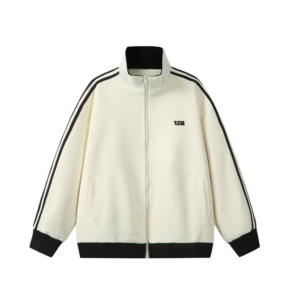 Cream zip-up track jacket with black sleeve stripes, black ribbed collar, cuffs and hem, and a small chest logo
