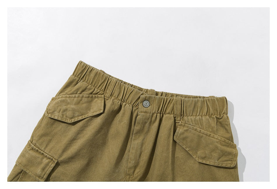 Close-up of olive-khaki cargo shorts showing the elastic waistband, button, and flap pockets.