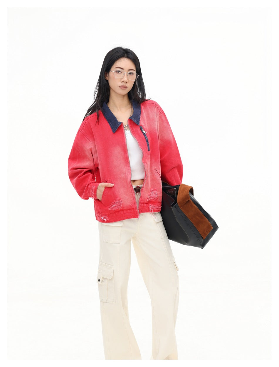 Model in the red washed zip jacket with navy collar, one hand in pocket, holding a black and brown bag