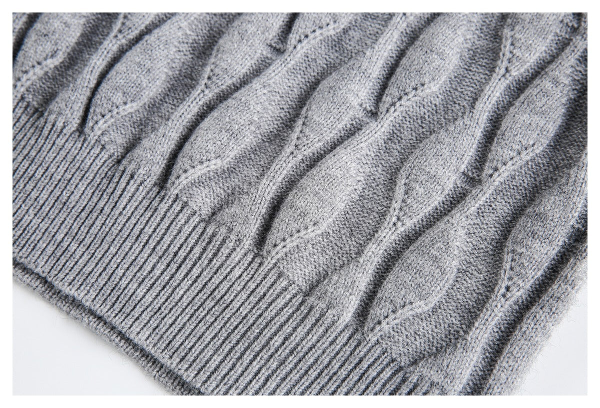 Close-up of the gray cable-knit sweater's ribbed hem and raised knit pattern.