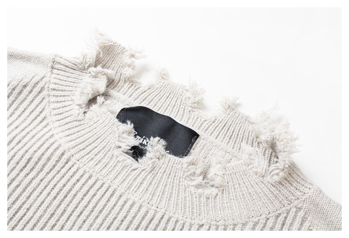 Close-up of an ivory rib-knit sweater neckline with distressed fraying and a black neck label.