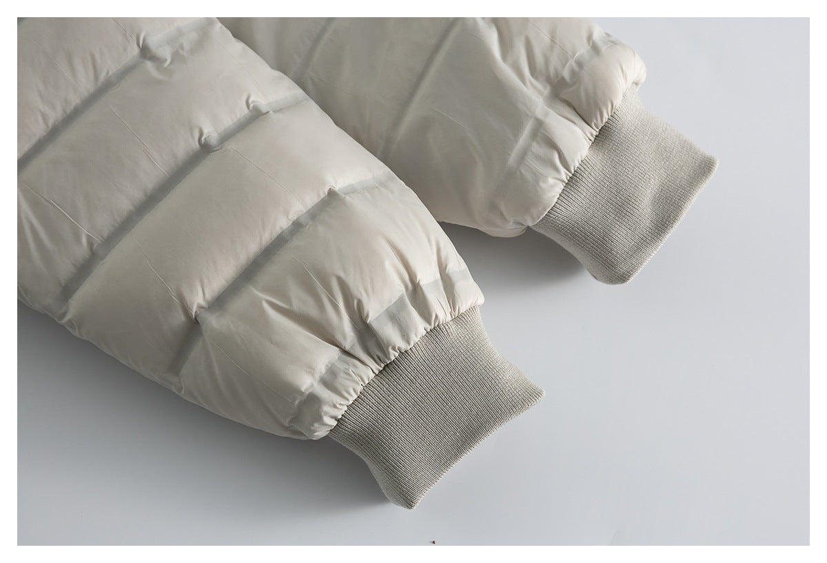 Close-up of the sleeves and gray rib-knit cuffs on a cream quilted puffer jacket.