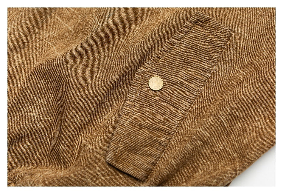 Close-up of a brown fabric pocket flap with a round metal button and visible stitching.