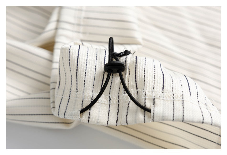 Close-up of a pinstriped garment cuff with a black elastic drawcord and toggle.